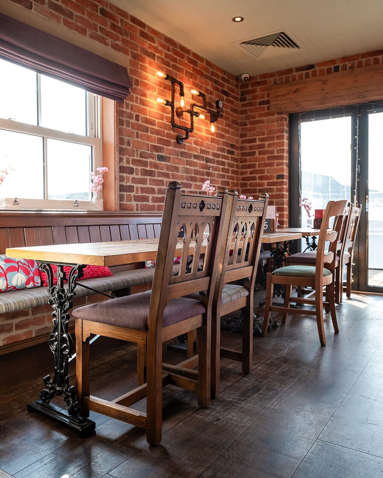 A dining area with brick walls, wooden chairs, a bench, and a table.