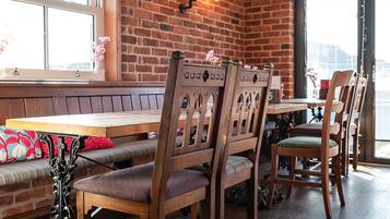 A dining area with brick walls, wooden chairs, a bench, and a table.