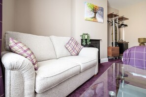 A living room with a sofa, a fireplace, a painting, and a bike rack.