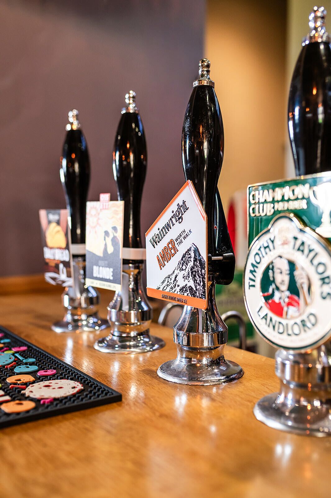 A bar with multiple taps, each labeled with different beer names and a sign indicating a special offer.