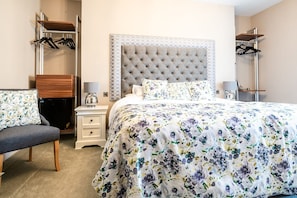 A hotel room with a bed, a nightstand, a dresser, a chair, and a wardrobe.