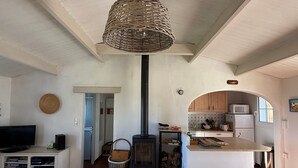 Ein gemütliches Wohnzimmer mit Fernseher, einem Esstisch und einer Küchenzeile mit Mikrowelle und Herd.