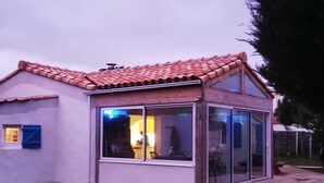 Ein Haus mit Ziegeldach, Glastür und Holzterrasse.