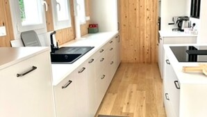 A narrow kitchen with white cabinets, a black sink, and a wooden floor. - Cozy house near the beach - 7 guests (La Guérinière)