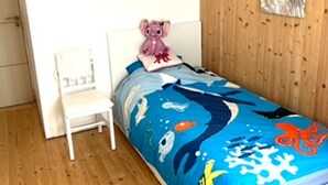 A bedroom with a bed featuring a blue ocean-themed bedspread, a white chair, a pink stuffed toy, and a framed picture on the wall. - Cozy house near the beach - 7 guests (La Guérinière)