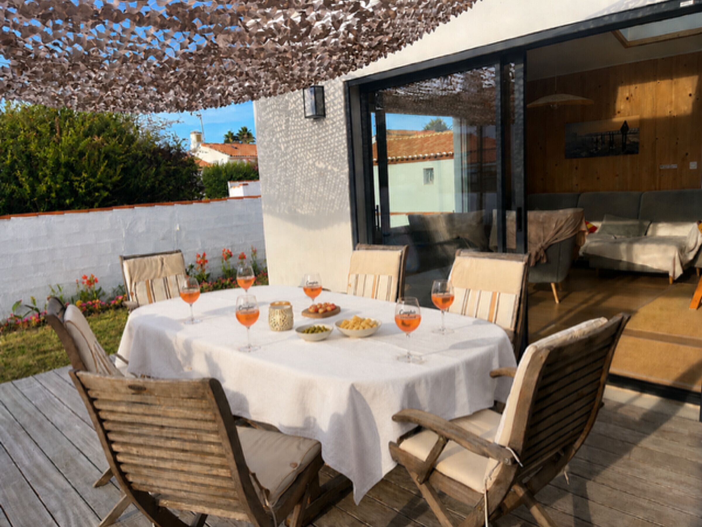 An outdoor dining area with a table set for four, surrounded by wooden chairs.