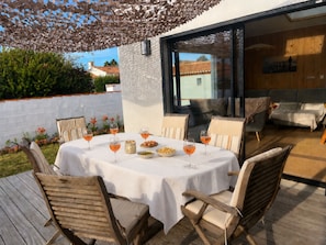An outdoor dining area with a table set for four, surrounded by wooden chairs. - Cozy house near the beach - 7 guests (La Guérinière)