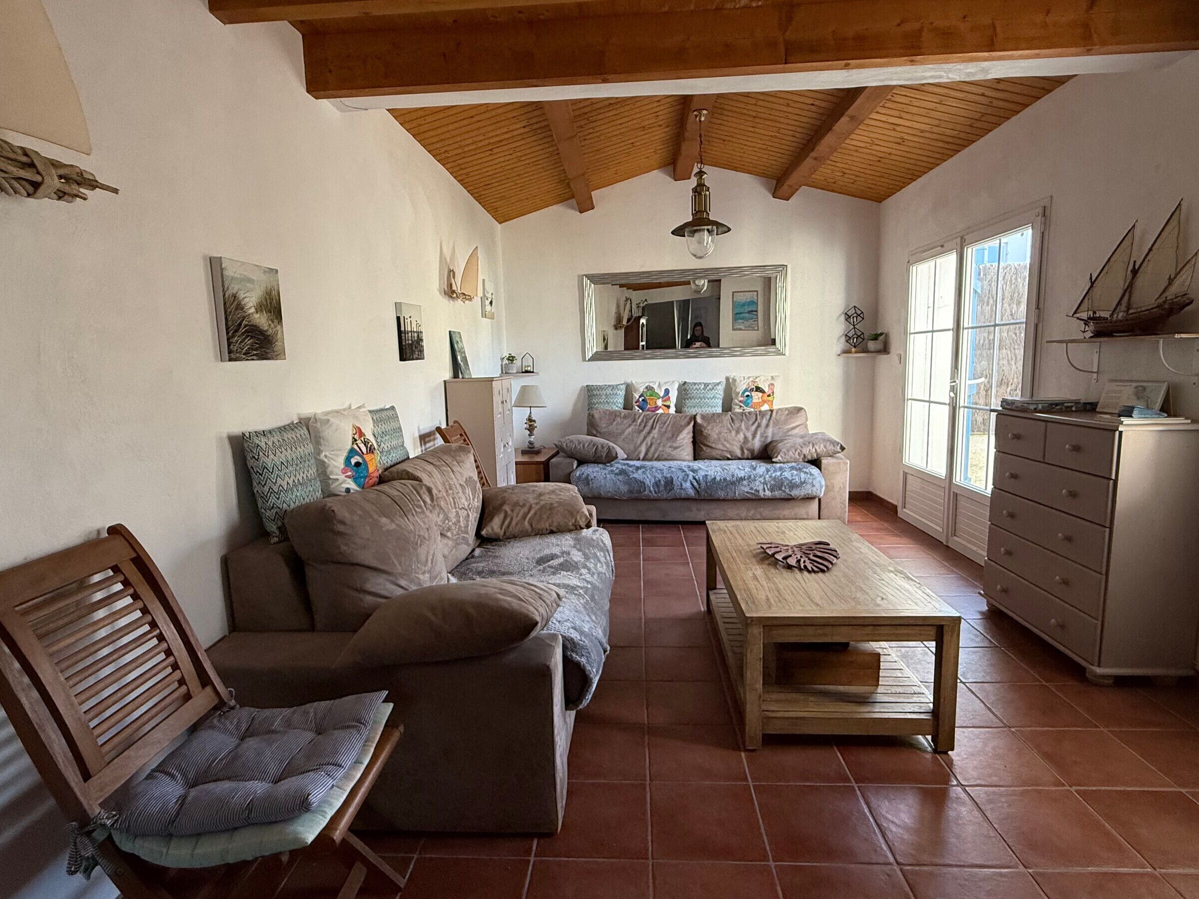 A living room with a sofa, chairs, a coffee table, a cabinet, and a large window.