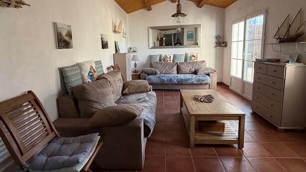 Un salon comprenant un canapé, des fauteuils, une table basse, un meuble et une grande fenêtre.