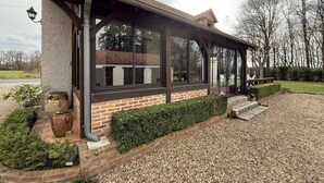 Een huis met een overdekte veranda, bakstenen muren en een grindpad.