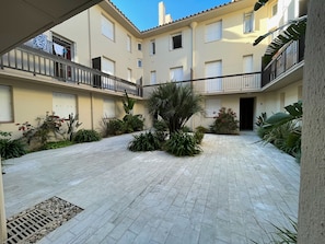 A courtyard with a tiled floor, surrounded by buildings with balconies and windows. - New studio near beach - 2 guests (Argelès-sur-Mer)