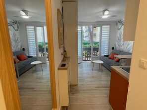 Un salon moderne avec un canapé gris, une petite table blanche et un meuble en bois.
