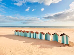 A row of beach huts on a sandy beach with a clear sky. - Bright apartment near the beach - 4 guests (Saint-Hilaire-de-Riez)