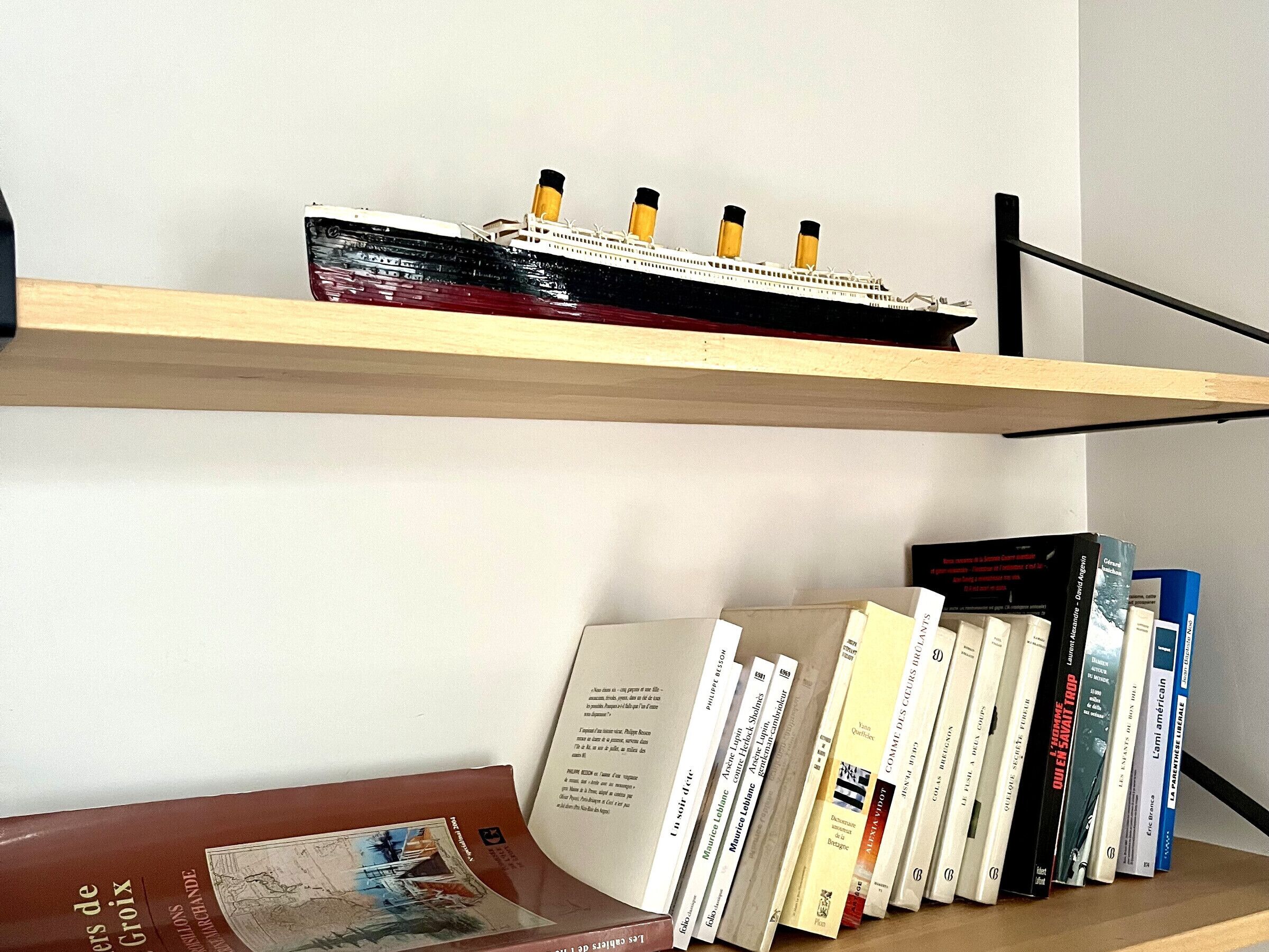 Une bibliothèque remplie de livres et un modèle de bateau.