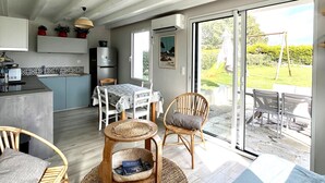 Eine moderne Küche mit Essbereich, einem Kühlschrank und Blick auf den Garten durch eine Glastür.