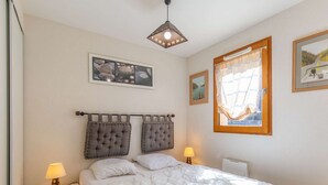 A bedroom with a bed, two bedside lamps, a window with a view, and a ceiling light fixture. - Apartment near village - 10 guests (Barèges)