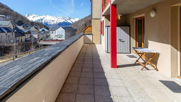 A balcony with a view of snow-capped mountains, a red door, and a small table. - Apartment near village - 10 guests (Barèges)