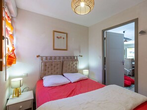 A bedroom with a bed, bedside lamps, a framed picture on the wall, and a door leading to another room. - Apartment near village - 10 guests (Barèges)