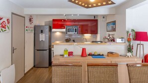 A compact kitchen with a refrigerator, microwave, and a hanging light fixture. - Apartment near village - 10 guests (Barèges)