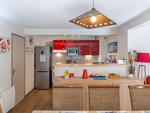 Eine kleine Küche mit Kühlschrank, Mikrowelle und einer Pendelleuchte.