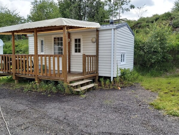 Une petite cabane avec une terrasse en bois et un porche abrité.