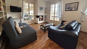 Ett vardagsrum med en soffa, ett soffbord, en tv och en bokhylla.