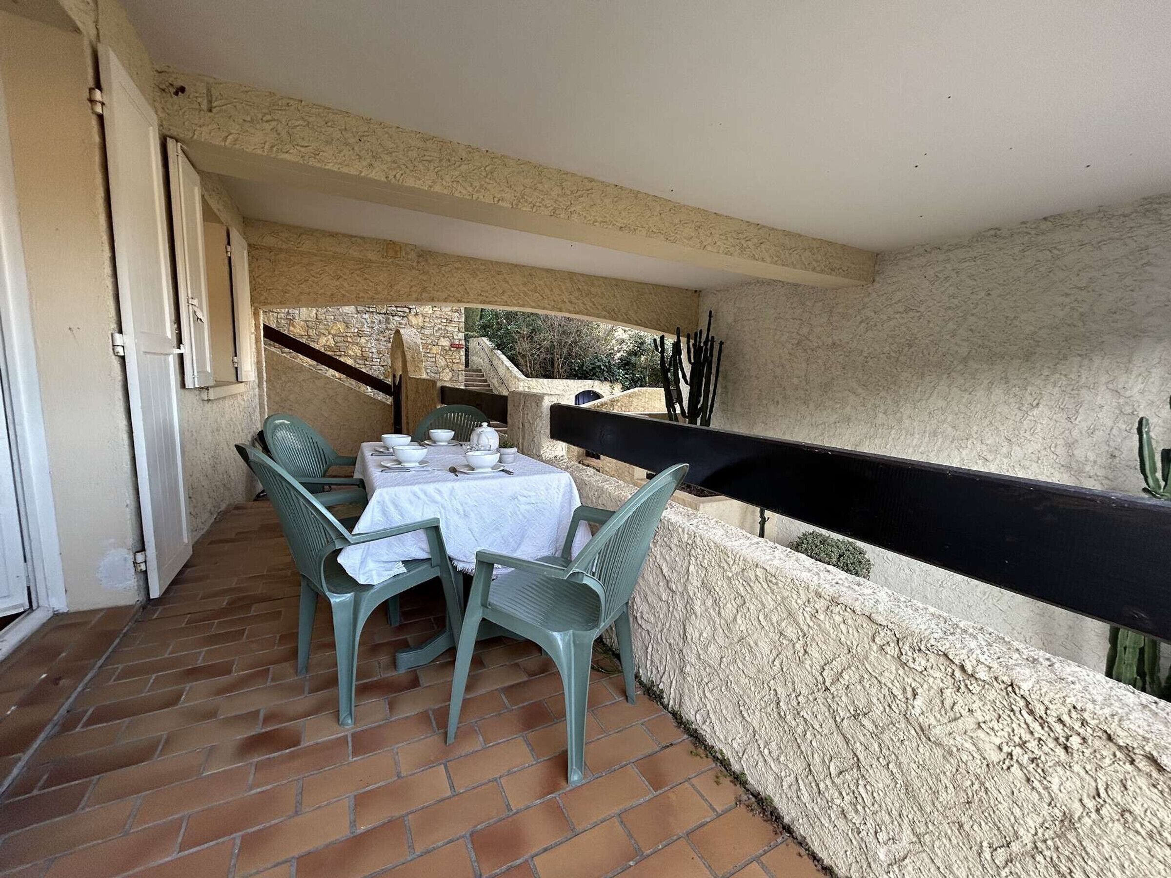 A patio with a table set for dining, surrounded by stone walls and a black railing.