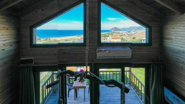 A wooden cabin with a large window and a hanging air conditioner. - Koru Wooden House (Gazipasa)