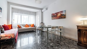 A hotel room with a bed, a dining table with chairs, a painting on the wall, and a wooden cabinet. - Livia's Vatican House - Metro Aurelia (Rome)