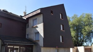 A multi-story building with a garage entrance, a flat roof, and a small garden area.