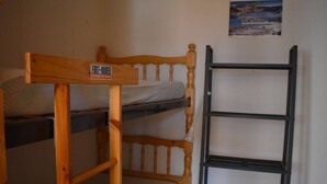 A bunk bed with a wooden headboard and a black metal ladder.