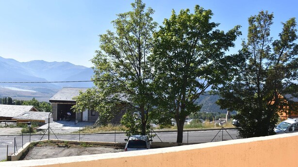 A residential area with a house, a tree, and mountains in the background.