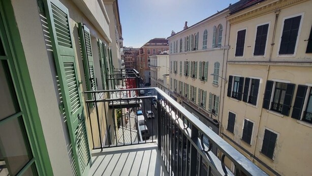 A balcony with a metal railing, a clear view of the street below, and buildings with classic architecture. - Villa Candide A409 by Avecoeur - Bail mobilité uniquement (Nice)