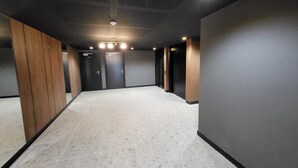 A hallway with a tiled floor, dark walls, and wooden paneling on one side. - Villa Candide A409 by Avecoeur - Bail mobilité uniquement (Nice)
