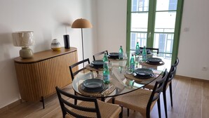A dining area with a glass table, woven chairs, and a green-framed window. - Villa Candide A409 by Avecoeur - Bail mobilité uniquement (Nice)