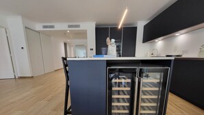 A modern kitchen with a central island, built-in appliances, and a black-framed glass door refrigerator. - Villa Candide A409 by Avecoeur - Bail mobilité uniquement (Nice)