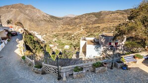 Un poble de muntanya amb cases de pedra, un carrer pavimentat i vista del vall.