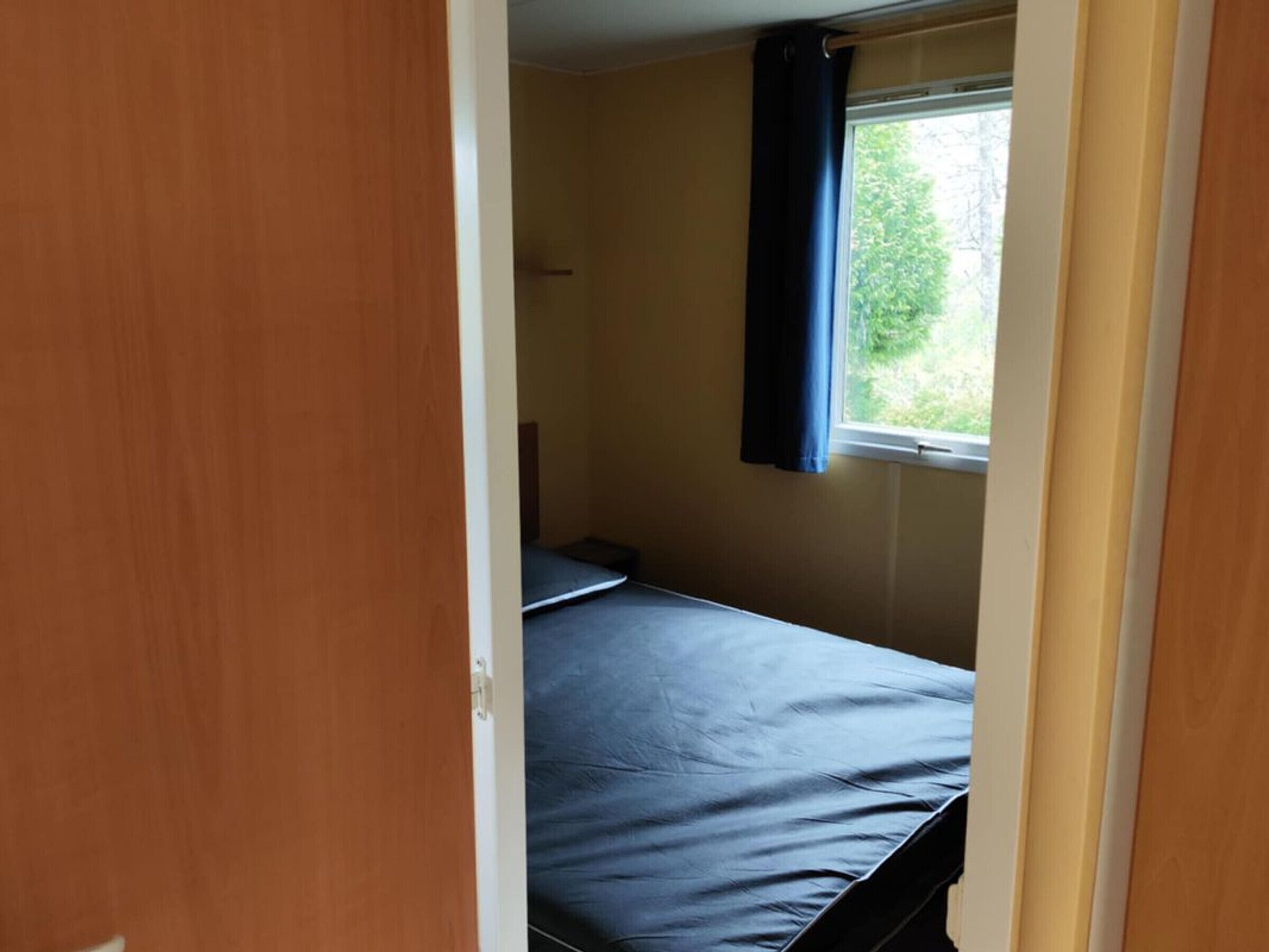 Um quarto com uma cama, uma janela com cortinas e uma porta.