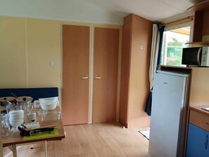 Et kompakt køkken med træskabe, en mikrobølgeovn og et spiseområde med et bord dækket til fire personer.