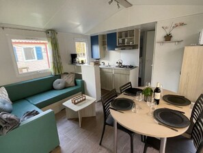 Ein kompakter Wohnraum mit Küchenzeile, Essbereich und Sofa.