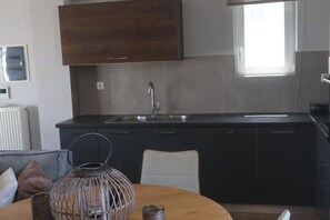Une cuisine moderne avec des meubles de couleur sombre, un évier en acier inoxydable et une fenêtre au-dessus du plan de travail.