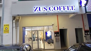 Un caffè chiamato ZUS COFFEE con una vetrina moderna e un ingresso in vetro.
