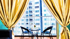 Un balcone con tavolo e sedie, vista su un grattacielo e tende.