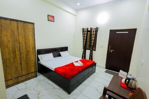 A bedroom with a bed, wardrobe, and a small table with a kettle.