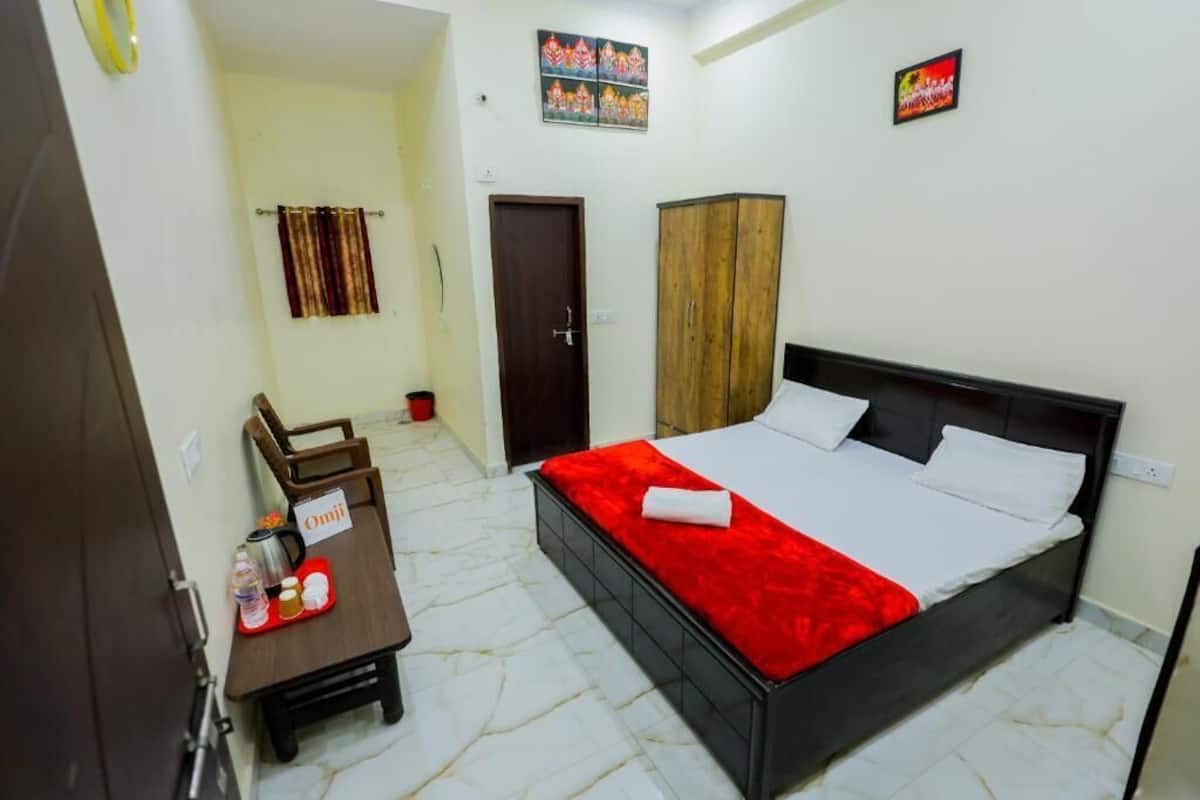 A bedroom with a bed, a desk with a chair, a wardrobe, and a door.