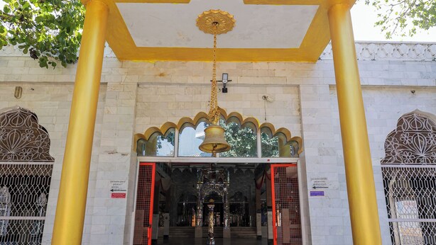 Een tempel ingang met een centrale boog, twee pilaren en een hangklok.