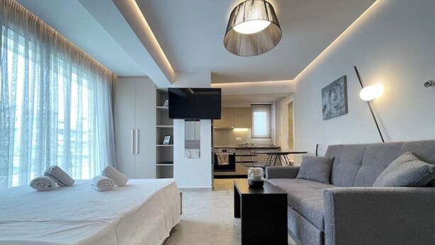 Une chambre d’hôtel moderne équipée d’un lit, d’un canapé, d’un téléviseur à écran plat, d’un coin cuisine et d’une table à manger.