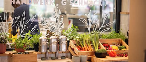 Un plan de travail de cuisine agrémenté de diverses plantes, de légumes et d’ustensiles de cuisine.