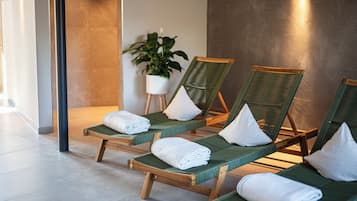 Un espace détente avec des chaises longues en bois, des serviettes blanches et une plante en pot.