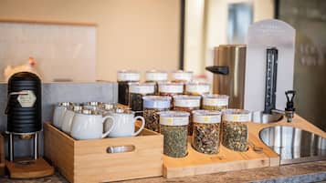 Un taulell de cuina amb cafeteres, tasses i pots de te.